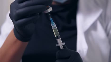 professional doctor in gloves and mask with medical syringe in hands, getting ready for injection. close up view