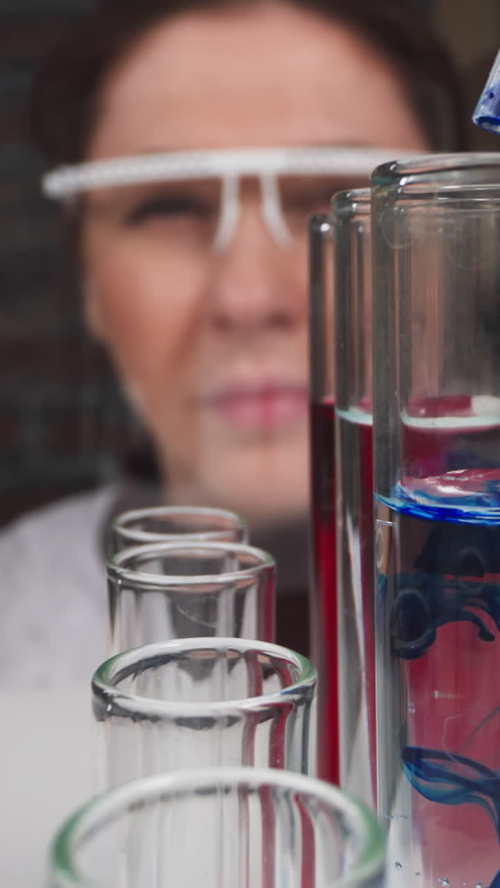 Female scientist drips blue catalyzer into test tube with transparent liquid in hospital slow motion. Probe lens shot of vaccine sample closeup