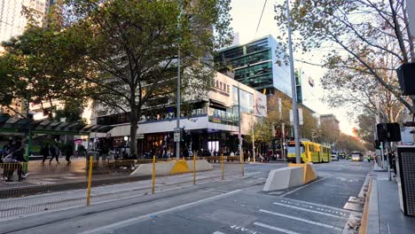 a yellow tram moves through melbourne city