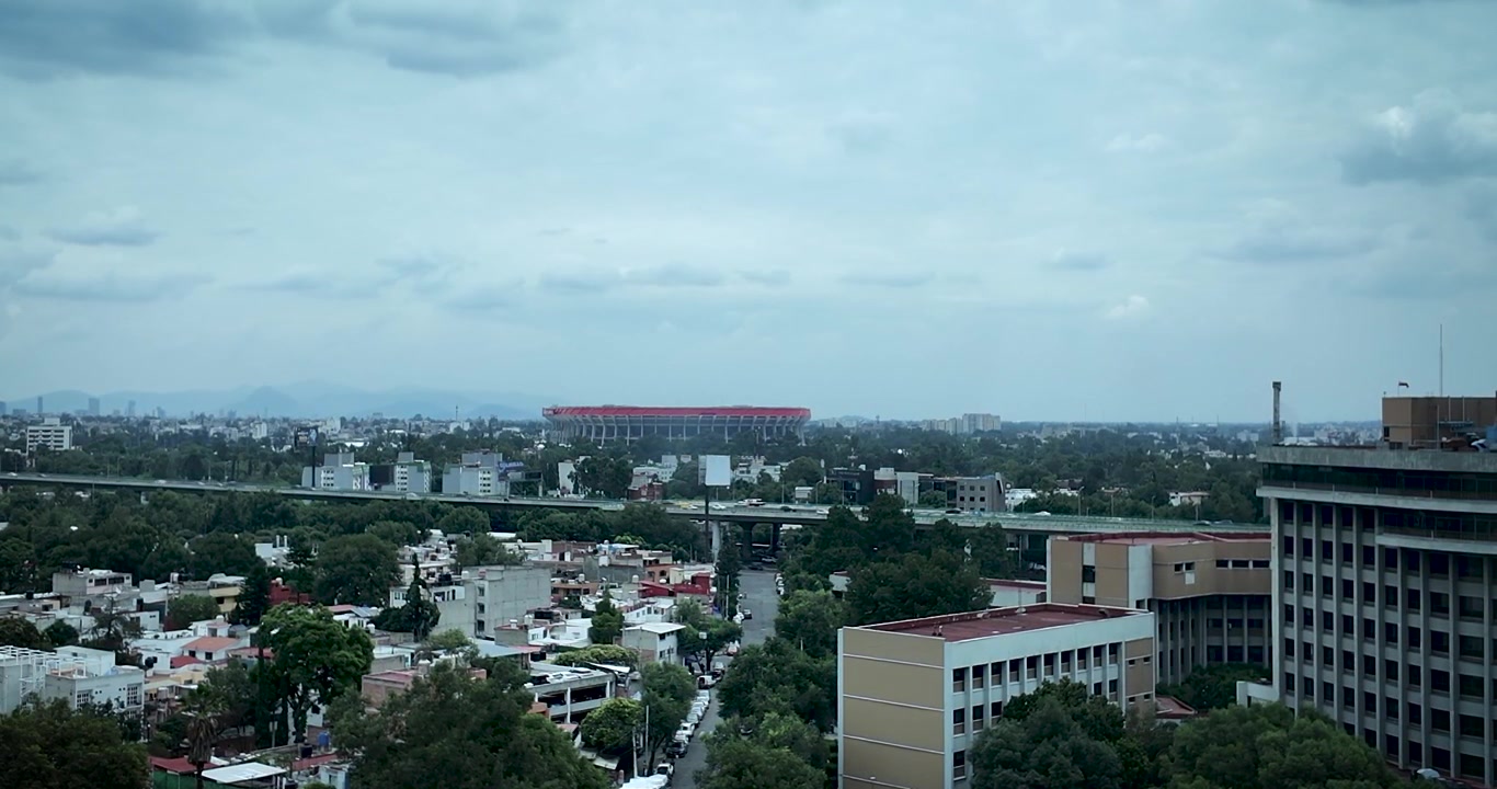 Vista cinematografica dello Stadio Azteca da una finestra di un edificio nel sud di Città del Messico durante la Coppa del Mondo FIFA 2026, che evidenzia l'iconica sede all'interno del paesaggio urbano