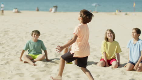 long shot of kid hitting soccer ball with feet on sea shore