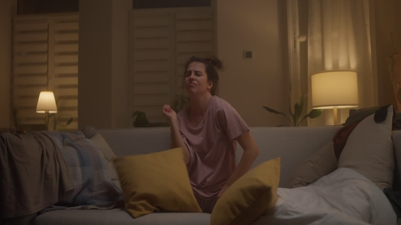 Kvinde leger med puder på en sofa om natten