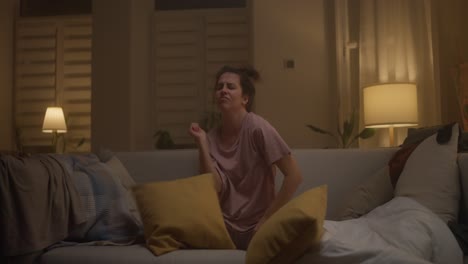 mujer jugando con almohadas en un sofá por la noche