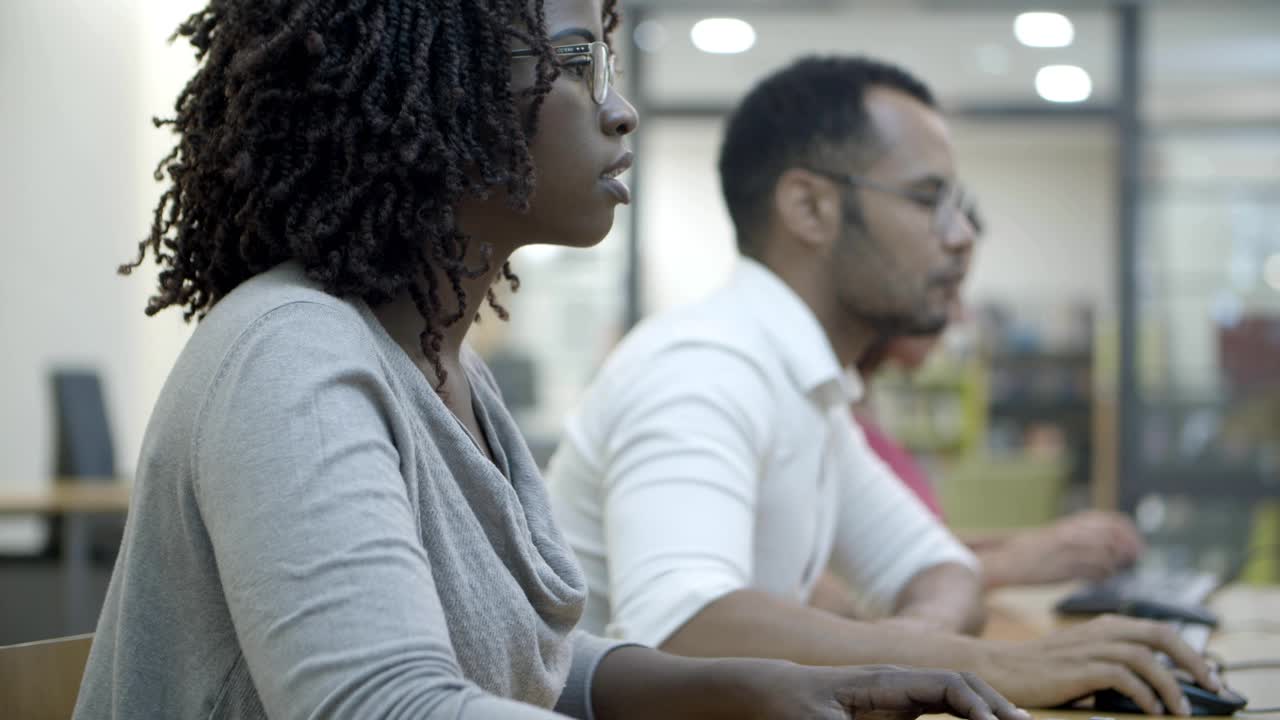 Side view of people sitting at tables and typing