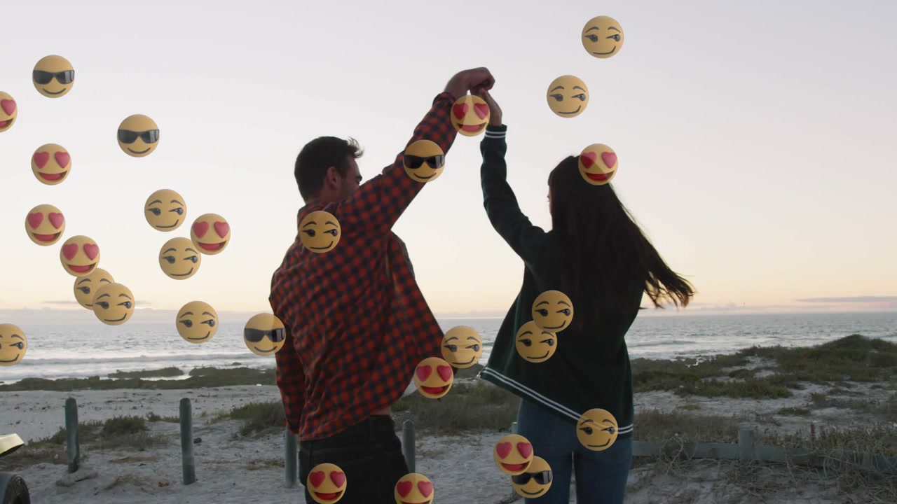 Man lifting woman's hand and twirling on sunset beach, with floating emoji icons rising for content