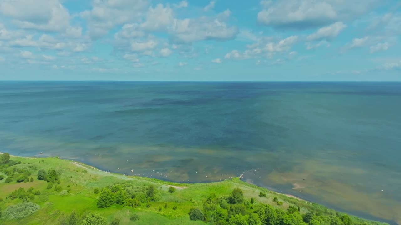 Flying inland from the sea to a green forested coastline.