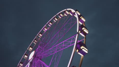 Violettes-Riesenrad,-Mittlere-Aufnahme,-Seitliche-Aufnahme-Auf-Bodenhöhe-Bei-Nacht