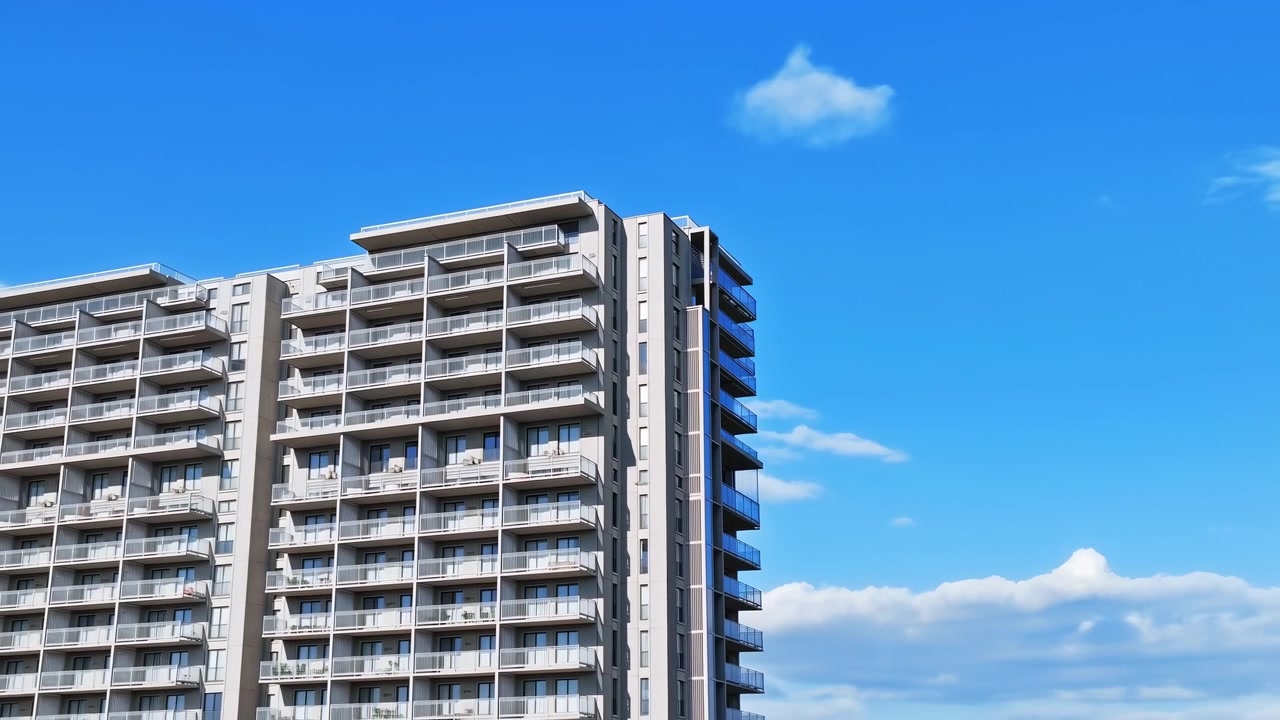 Edificio de apartamentos moderno bajo cielo despejado. Balcones soleados y ventanas de cristal reflejan azul vivo, blanco nítido.