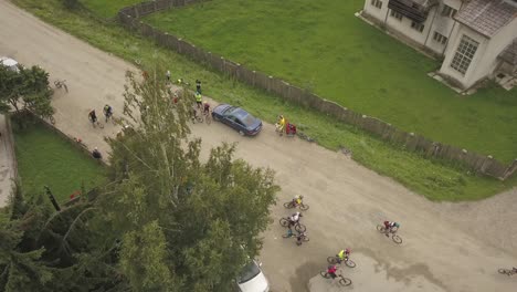 aerial shot panning over cyclists departing a rural town for a race up a mountain in romania