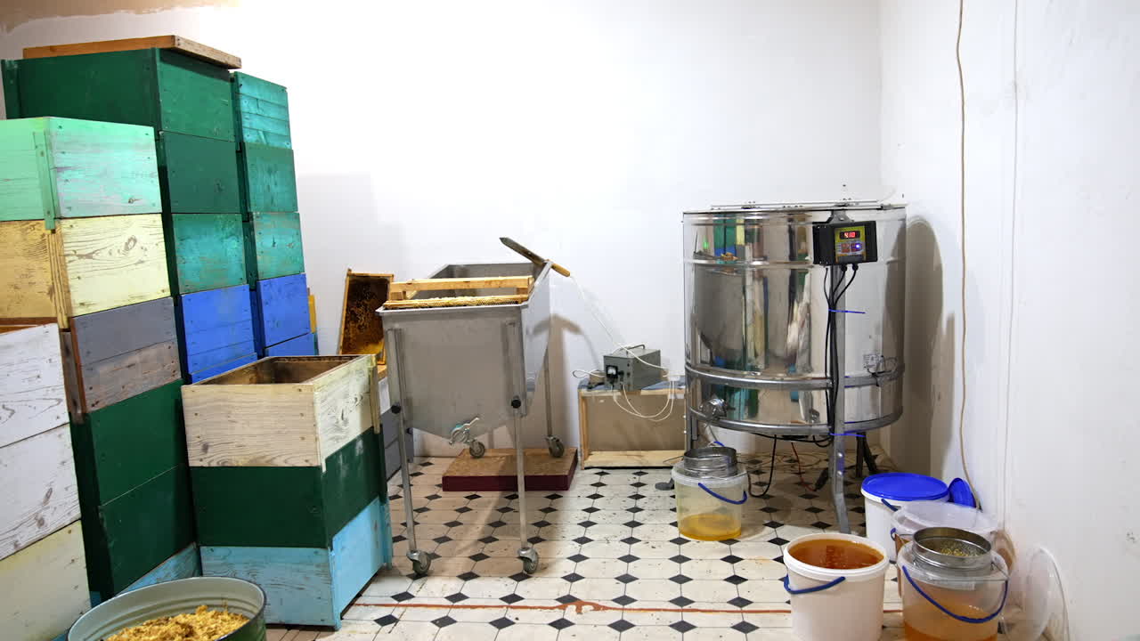 Apiary premise with necessary equipment for extracting honey. Buckets of fresh organic honey standing near the centrifuge.
