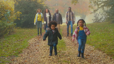 portrait of smiling multi-generation family walking through autumn countryside together