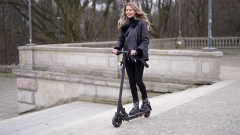 young woman riding an electric scooter in a park