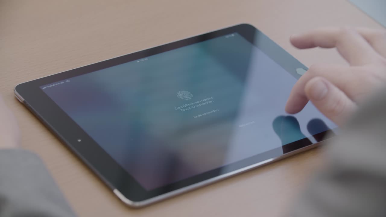 A person unlocking a tablet using touch ID in an office setting