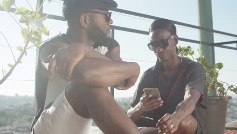 pensive gay sitting on rooftop while his boyfriend using phone