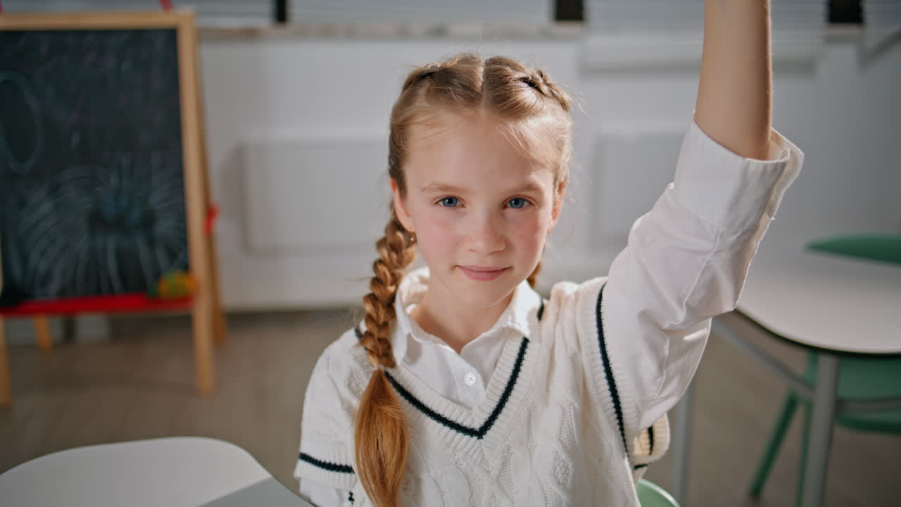 Clever girl raising hand answering question at lesson portrait. Pupil learning