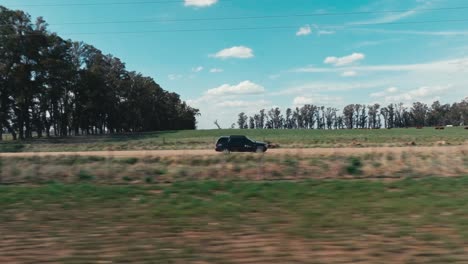 Ein-Jeep-Fährt-An-Einem-Sonnigen-Tag-Mit-Wolken-Am-Himmel-Durch-Eine-Landschaft-In-Argentinien