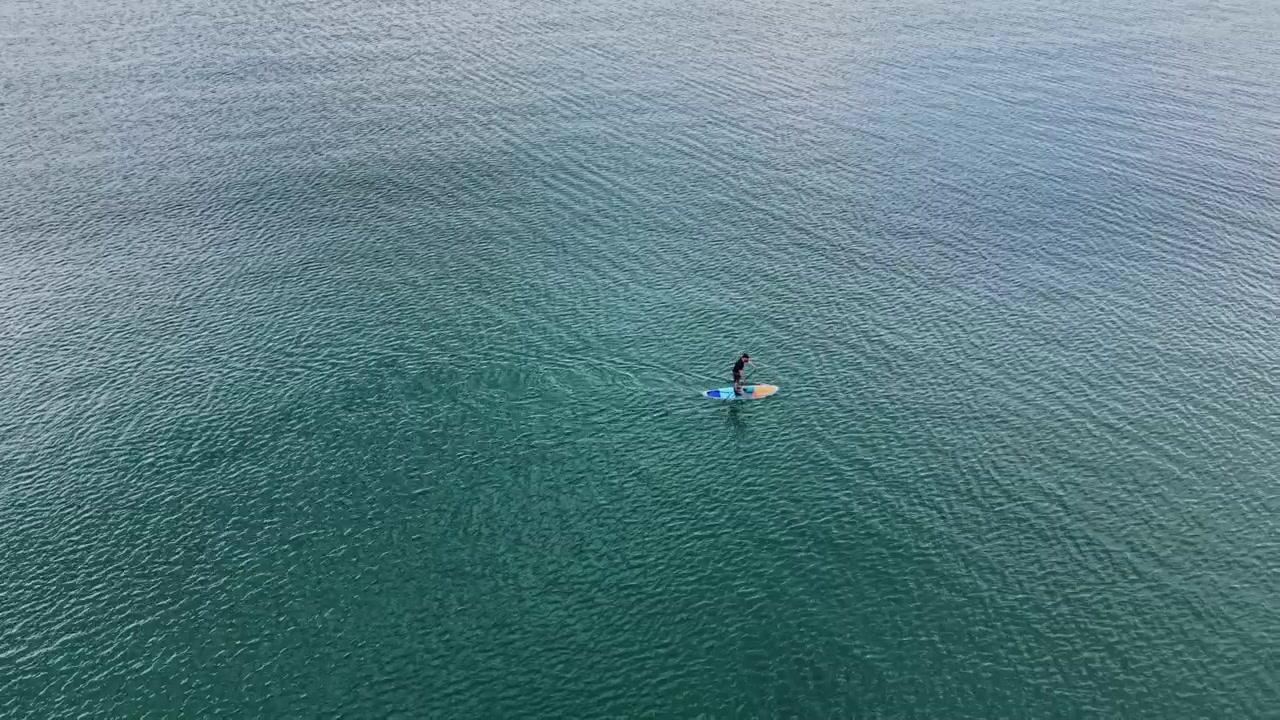 Persona che fa paddleboard in acque calme durante il giorno soleggiato