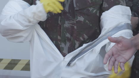 brazilian soldier removing protective hazmat gear after sanitizing a hospital