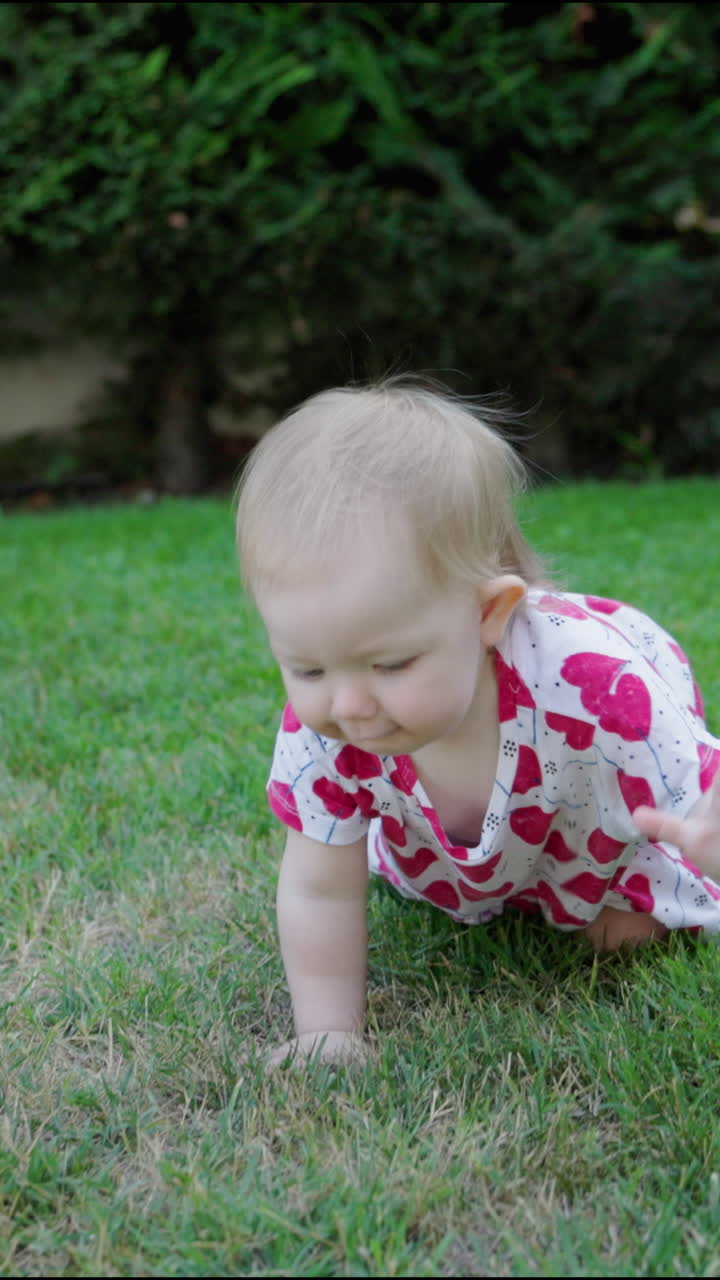 Bambina che sorride gattonando sull'erba verde in giardino all'aperto