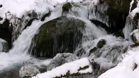 Nahaufnahme-Eines-Kleinen-Wasserfalls,-Der-über-Felsen-Und-Eis-In-Einem-Schneebedeckten-Wald-Im-Chugach-State-Park,-Alaska,-Fließt