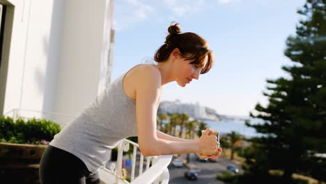 young woman leaning on balcony railing and having coffee at home 4k