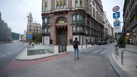 Lone-tourist-walking-through-empty-streets-of-Budapest,-stopping-to-take-a-photo