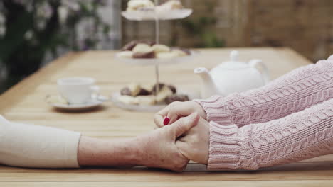 Zwei-Frauen-Halten-Sich-An-Den-Händen,-Während-Sie-Draußen-Sitzen