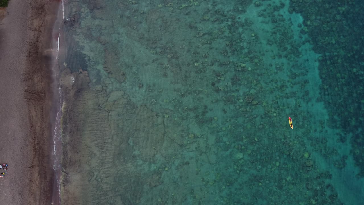 Video aereo con drone di turisti che remano in un kayak colorato in una destinazione esotica tropicale hawaiana con acque oceaniche calme e turchesi