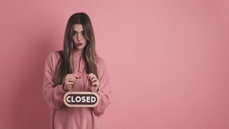 frustrated young woman standing and showing closed signboard