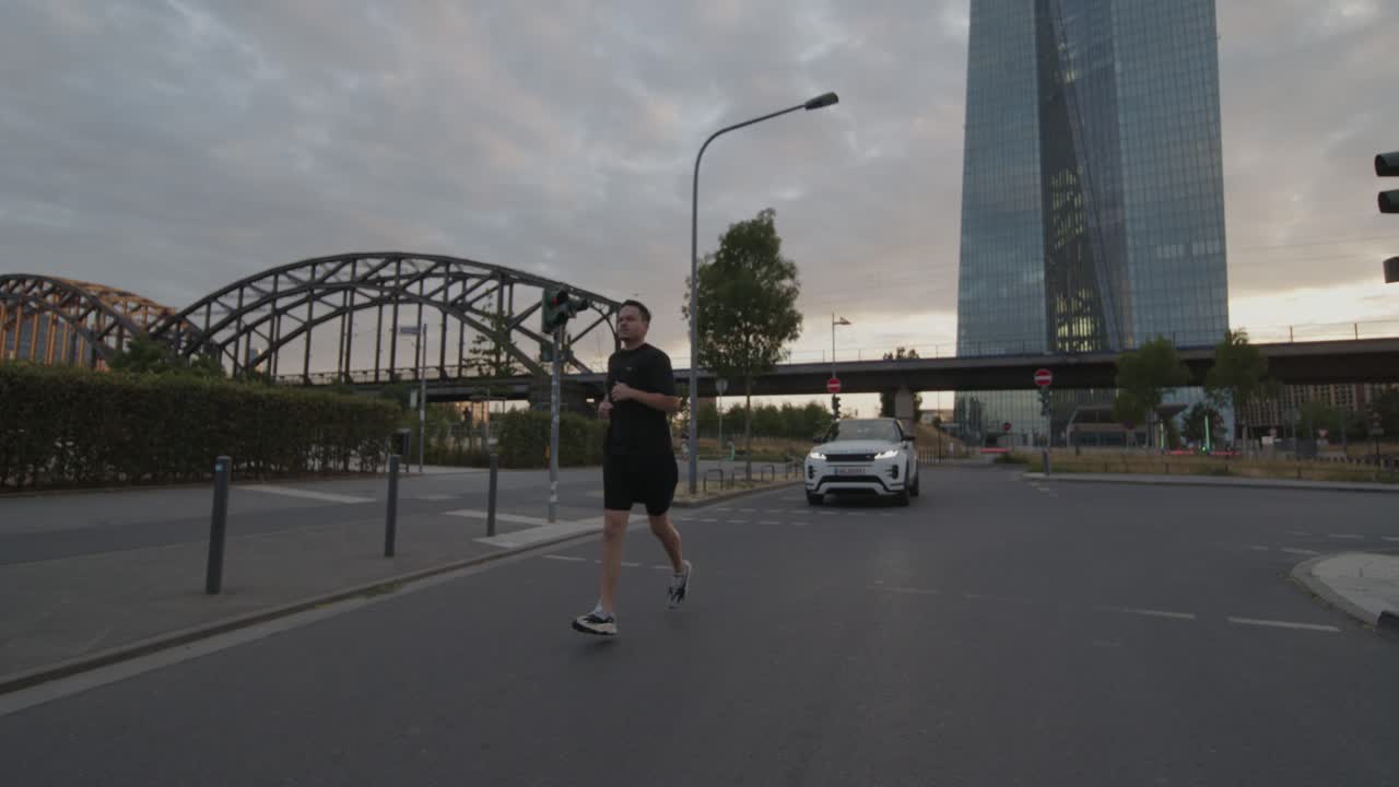 un atleta va corriendo, corriendo por un puente en el principal en frankfurt con el horizonte en el fondo