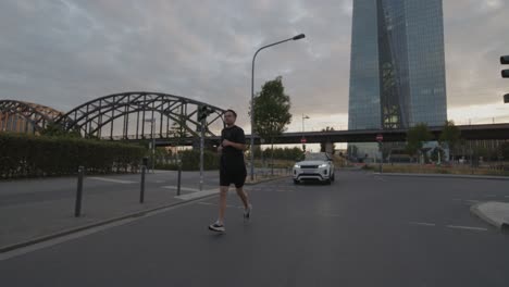 an-athlete-goes-running,-jogging-on-a-bridge-on-the-Main-in-Frankfurt-with-the-skyline-in-the-background