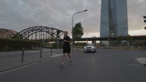 an athlete goes running, jogging on a bridge on the main in frankfurt with the skyline in the background