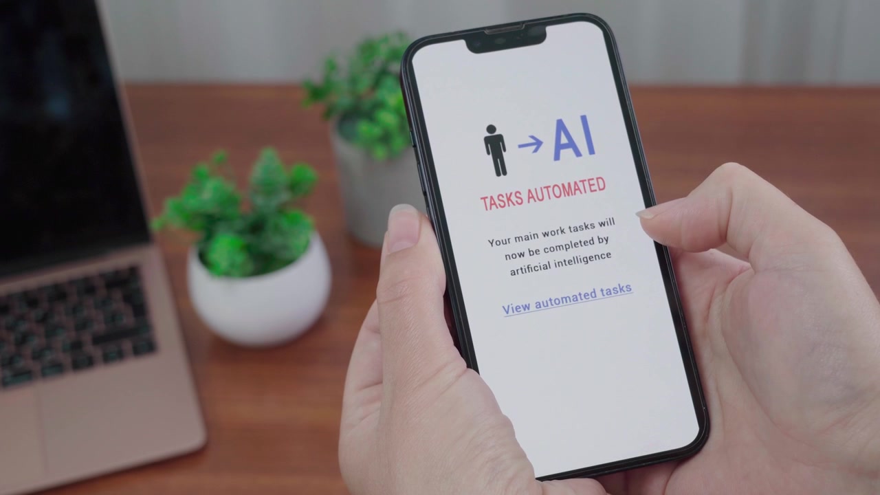 Nærbillede af en automatiseret besked om opgaver på en smartphone, der forklarer, at primære arbejdsopgaver nu vil blive udført af AI.