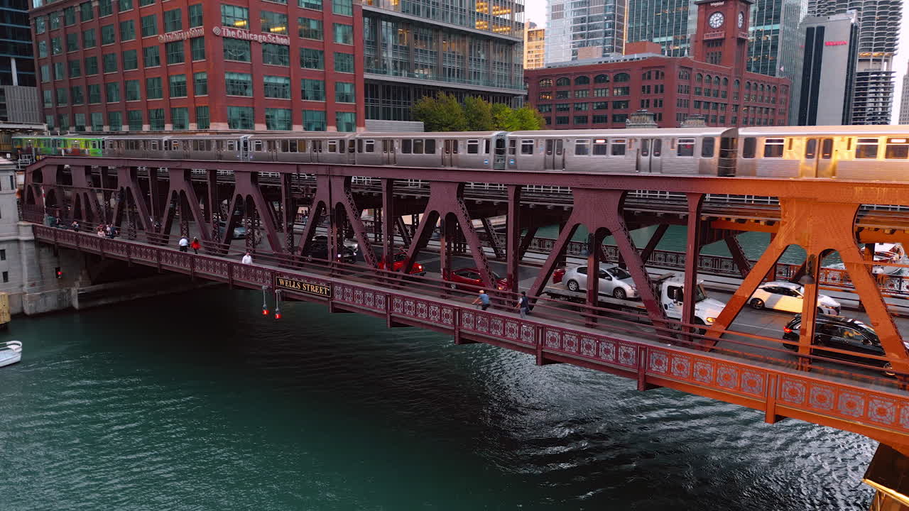 Chicago, USA, 29 June 2025: Train, cars and people move by the bridge across the Chicago River. A little boat floats by the waterscape. Aerial view