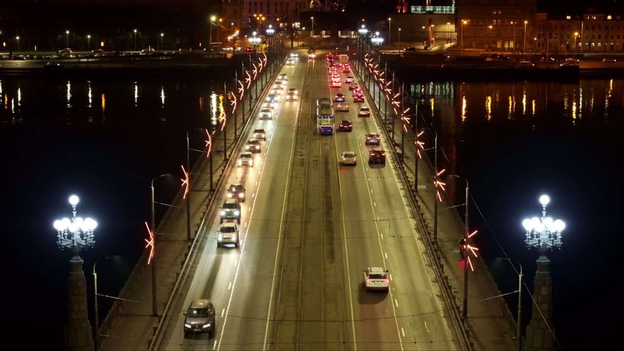 Traffic crossing Akmens Bridge at night - glowing lamps, tram, urban reflections