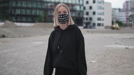 pretty blonde girl with face mask walking in urban neighborhood