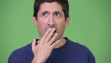 hispanic man covering mouth and looking guilty