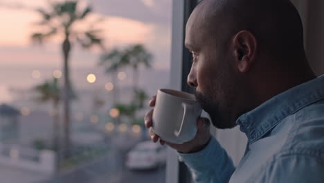 attractive-man-drinking-coffee-looking-out-window-in-hotel-room-enjoying-early-morning-view-at-sunrise-contemplating-future-planning-ahead