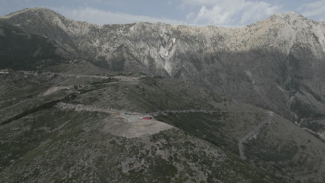 Drohnenaufnahme-Vom-Aussichtspunkt-Llogara-In-Der-Nähe-Von-Tirana-In-Albanien-An-Einem-Bewölkten-Tag-Im-Schatten-Mit-Menschen-Und-Touristen,-Die-Auf-Einem-Roten-Skulpturenstamm-über-Das-Tal-Wachen