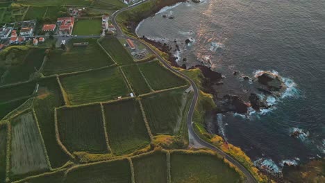 coastal village mosteiros at sunset with lush green fields and winding roads, aerial view