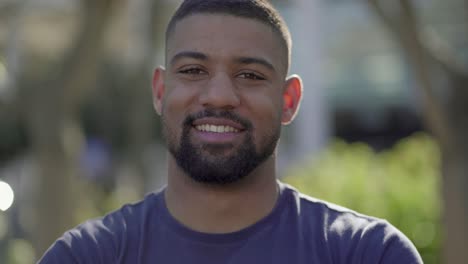 primer plano de un joven en el parque mirando a la cámara, sonriendo