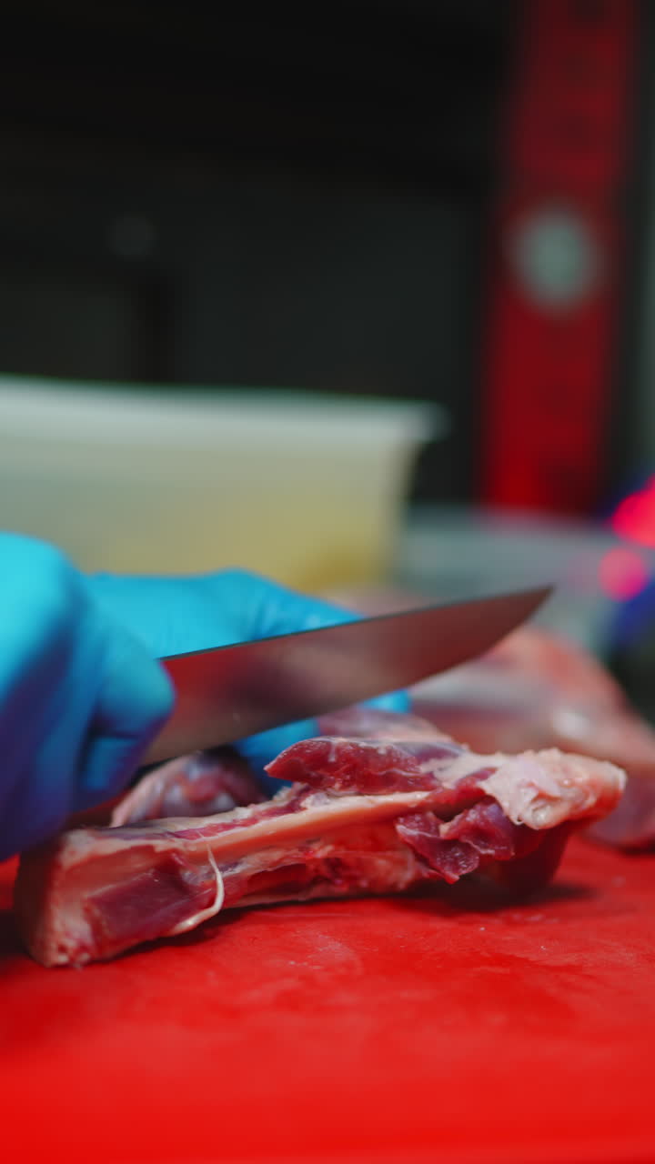Professional Chef Cutting Raw Meat with Knife on Red Board