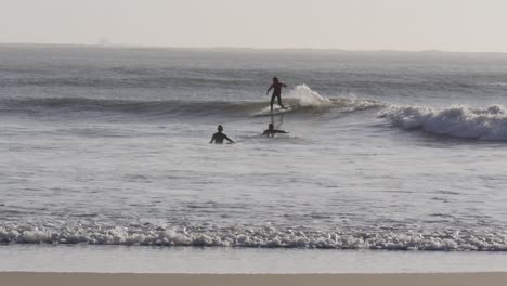 4k wide static shot of surfer riding wave during golden hour
