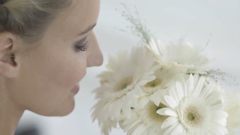 Beautiful-bride-smelling-her-bouquet-of-daisies-