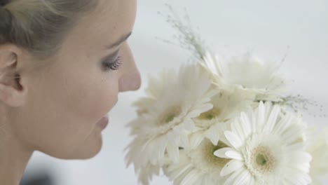 beautiful bride smelling her bouquet of daisies