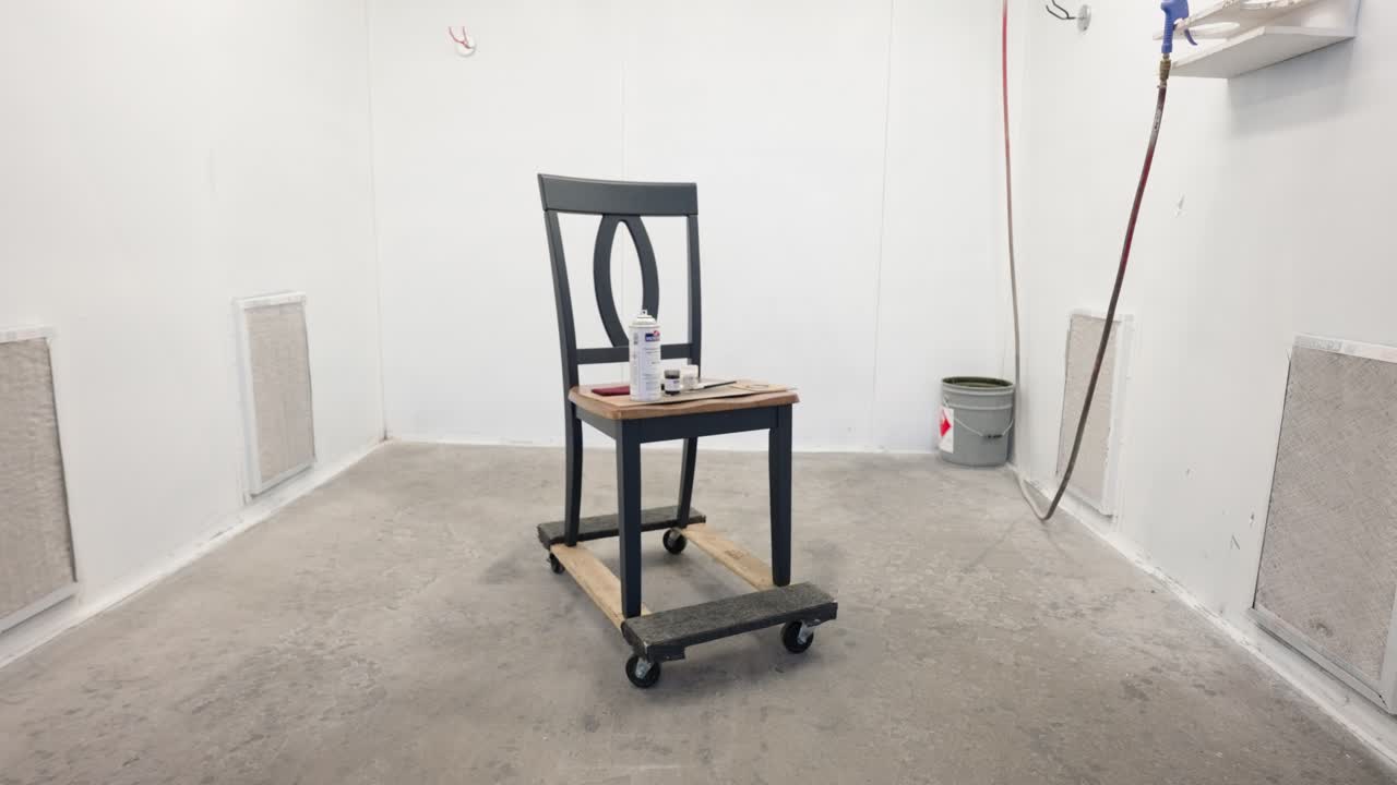 Slow motion close zoom reveals dining chair in paint booth, factory interior