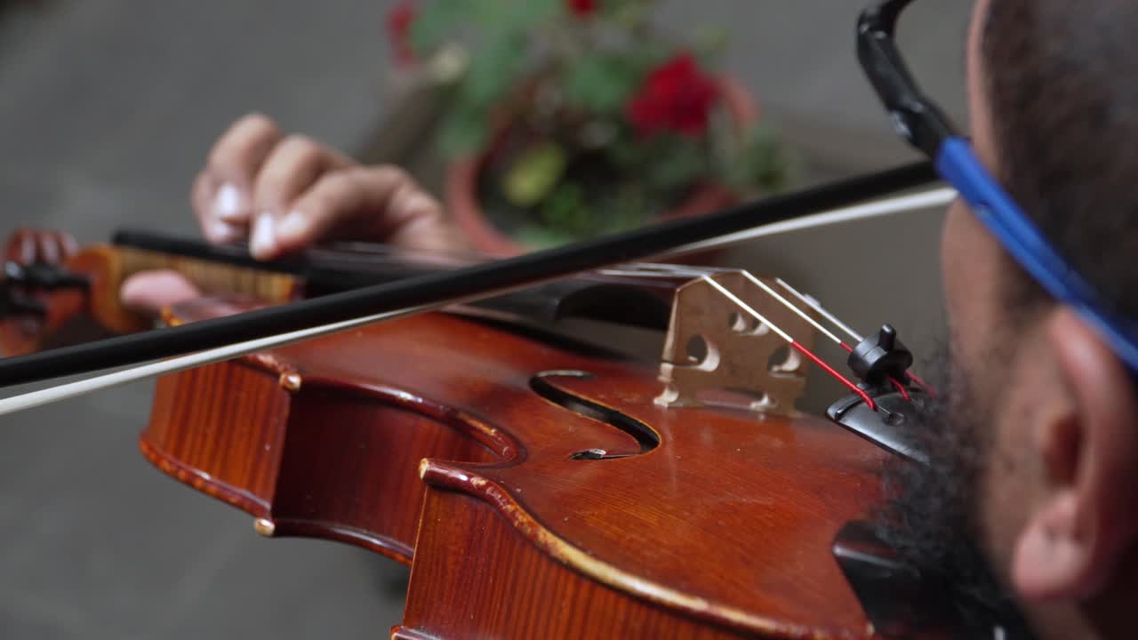 Man playing the viola with a bow on strings, a close up