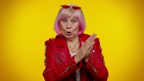 a woman with pink hair, wearing a red jacket and sunglasses, poses for a portrait