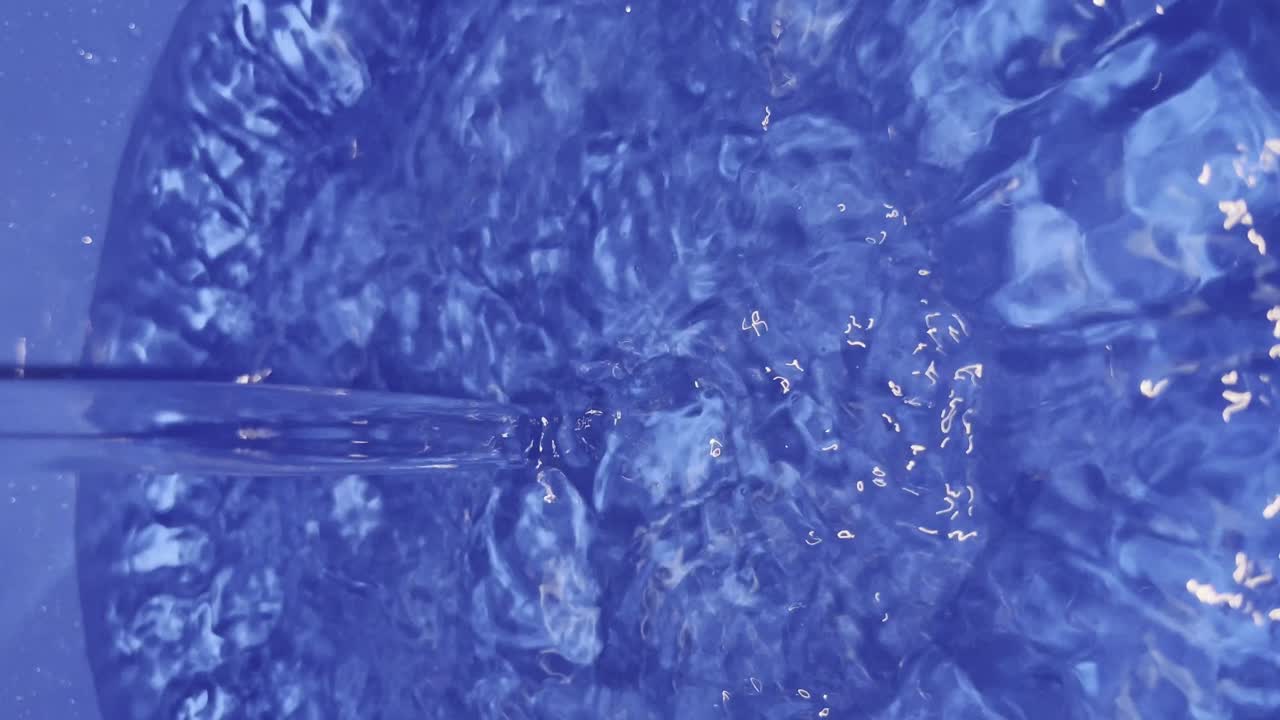 Vista aproximada da água enchendo um balde azul.
