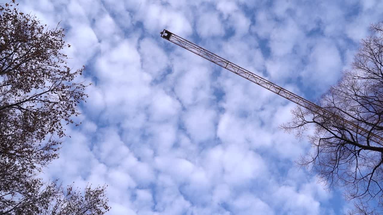 푸른 구름낀 하늘을 가로질러 천천히 움직이는 건설 크레인을 올려다보며